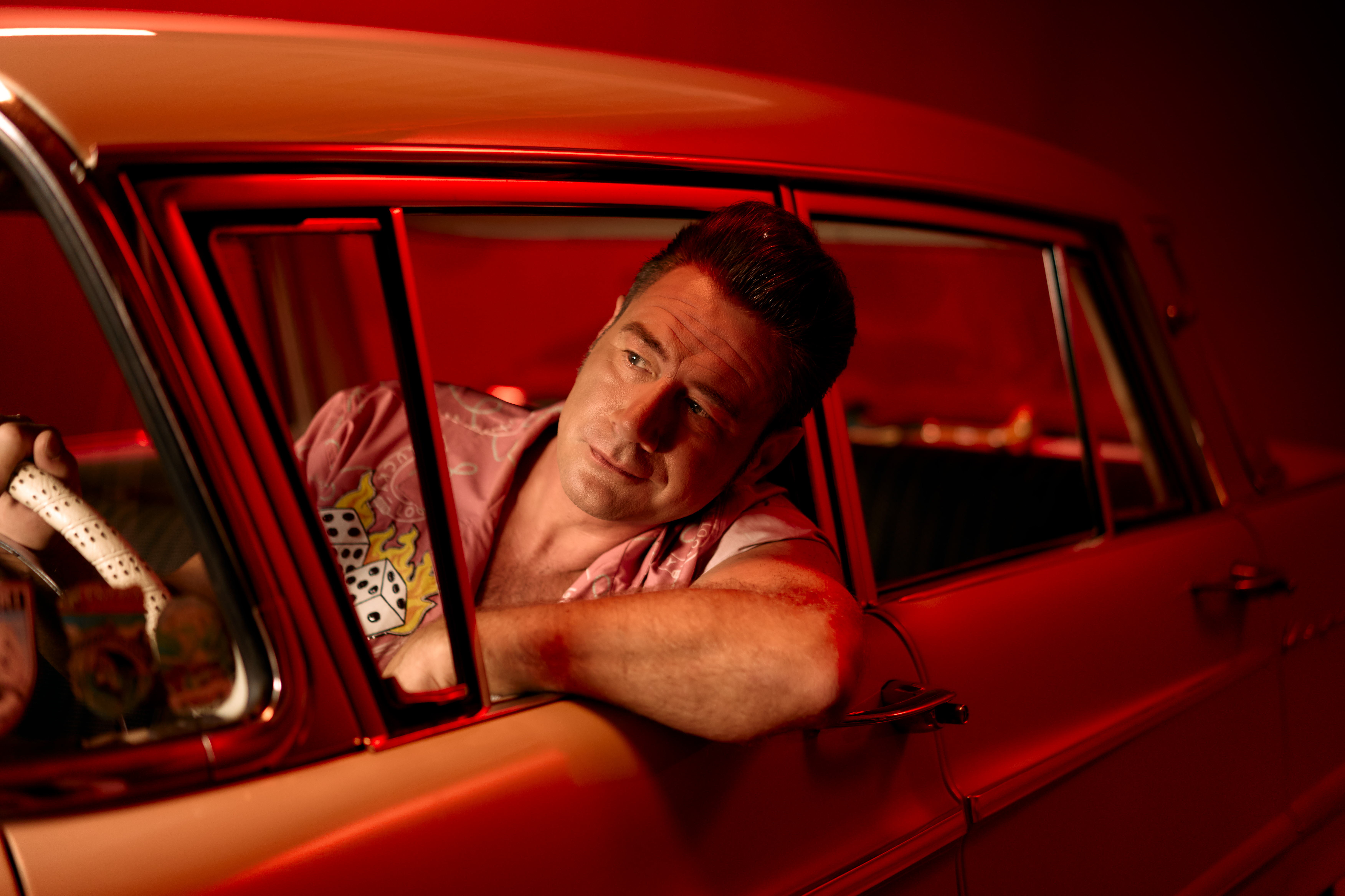 Dick Brave schaut aus dem Seitenfenster eines Oldtimers