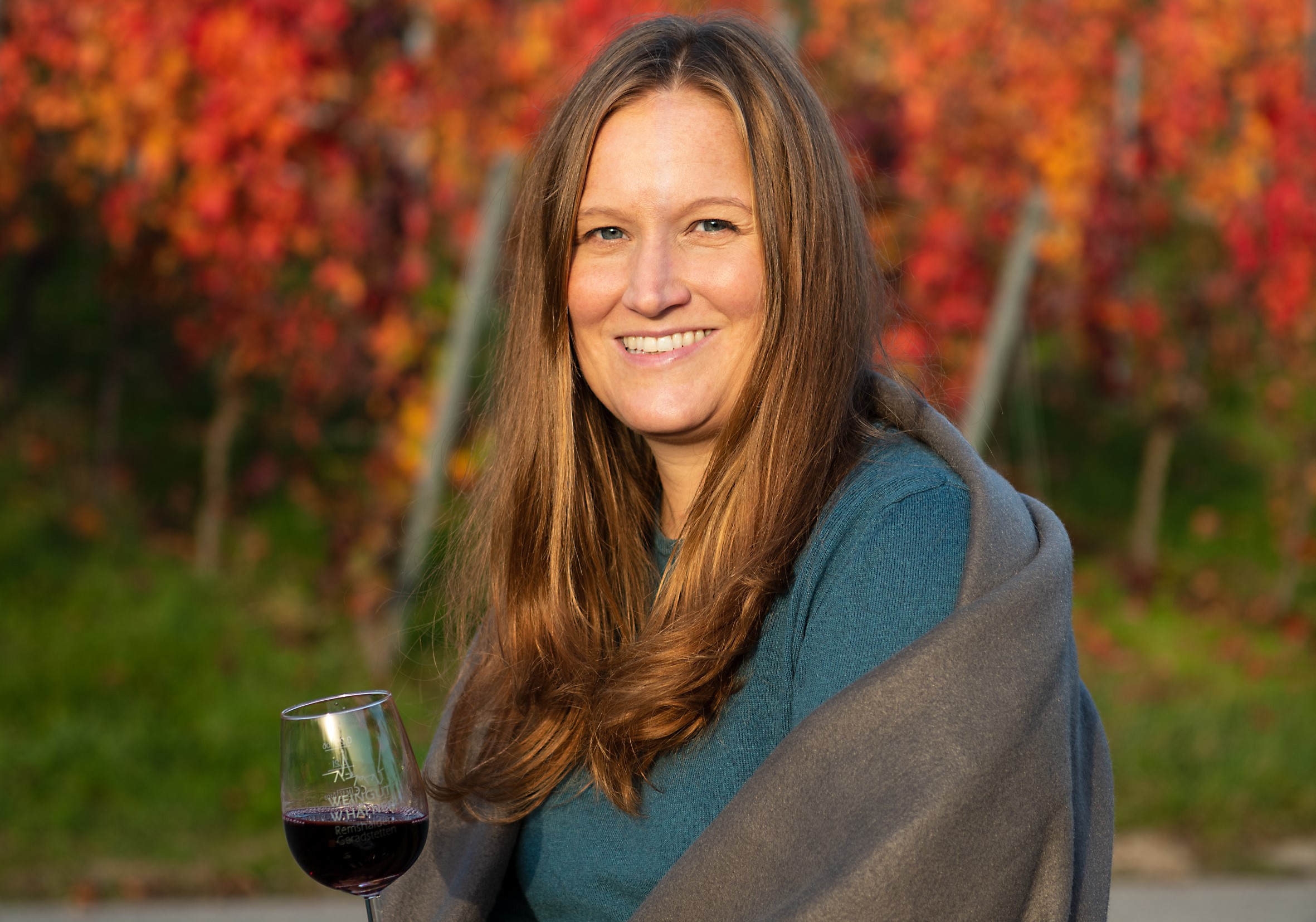 Frau Herbst vom Weingut Häfner vor einem rot gefärbten Weinberg